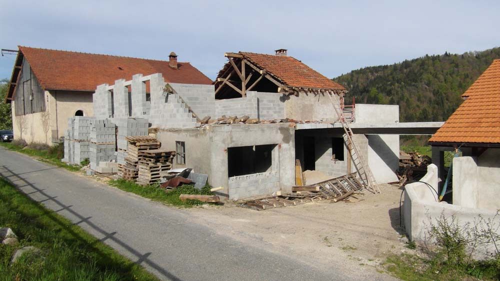 Chantier de rénovation d’une maison avec surélévation en parpaing et toiture partiellement démontée – AK Rénovation, Pays de Gex